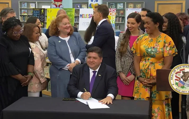 man signing document with a crowd of people around him